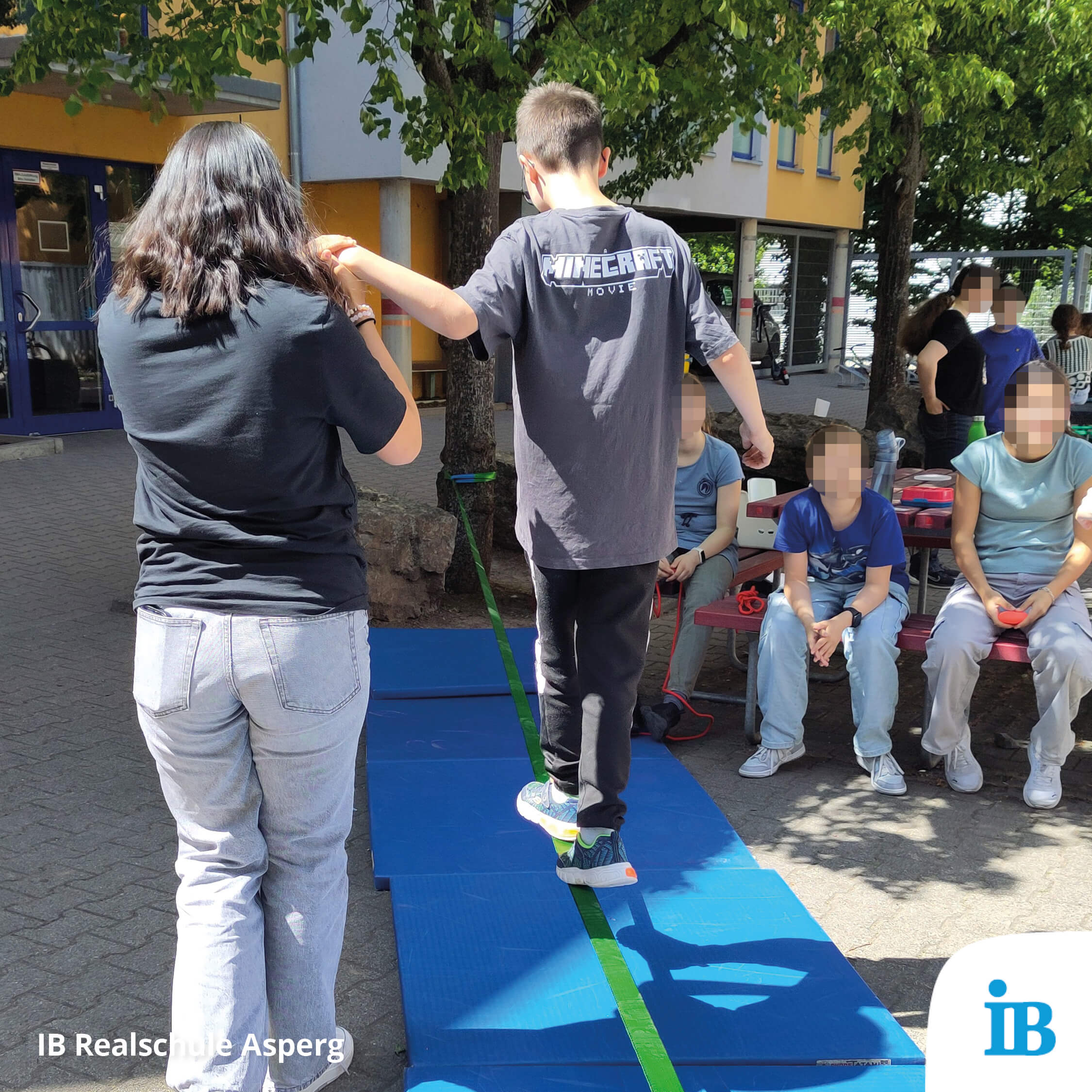 Ein Junge balanciert auf einer Slackline, während eine Frau ihn unterstützt, umgeben von Zuschauern.